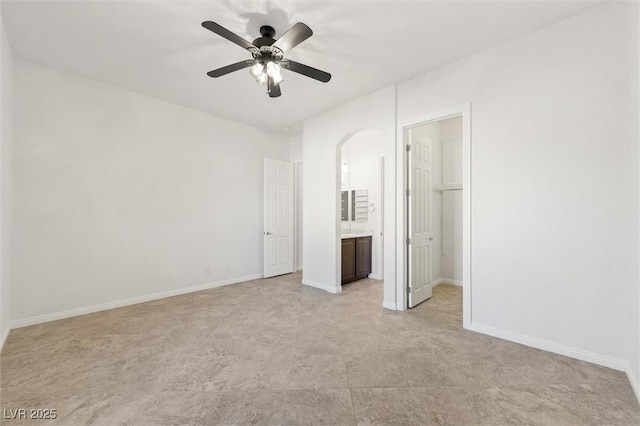 unfurnished bedroom with ensuite bath, ceiling fan, a spacious closet, and a closet