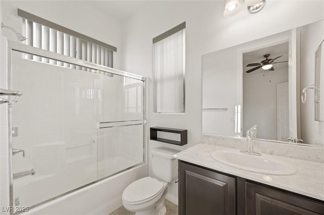 full bathroom featuring toilet, bath / shower combo with glass door, ceiling fan, and vanity