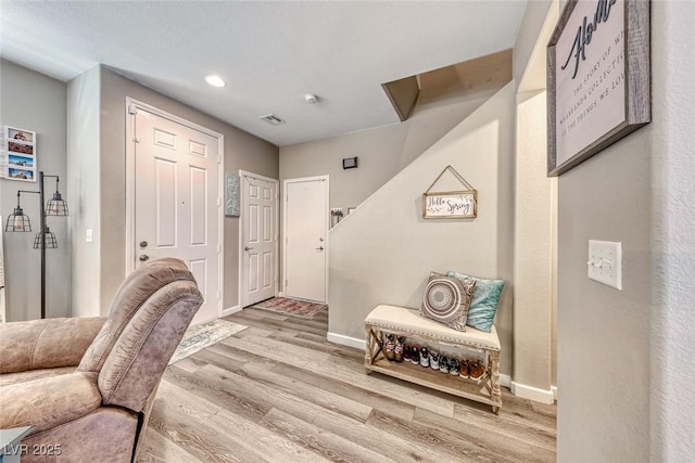 living area with wood finished floors, visible vents, and baseboards