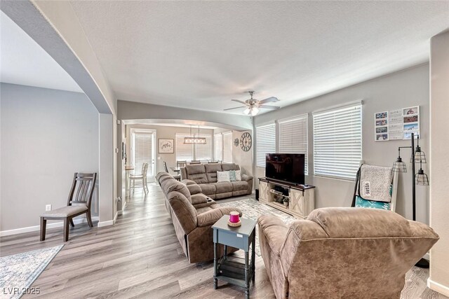 living room with ceiling fan, light hardwood / wood-style floors, and a textured ceiling