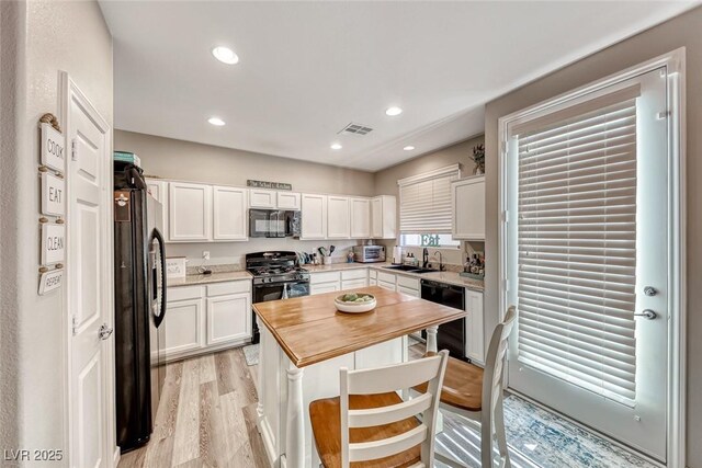 kitchen featuring black appliances, light hardwood / wood-style floors, white cabinetry, and sink