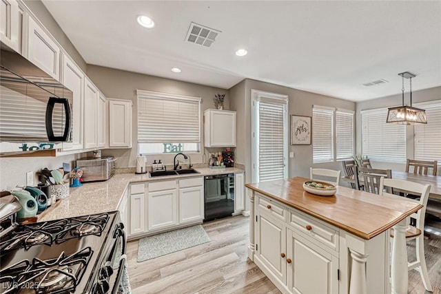 kitchen with sink, white cabinetry, a center island, pendant lighting, and black appliances