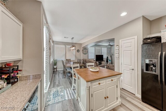 kitchen featuring light hardwood / wood-style flooring, pendant lighting, black fridge, white cabinets, and ceiling fan