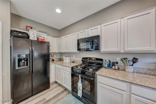 kitchen with white cabinets, light stone countertops, light hardwood / wood-style floors, and black appliances