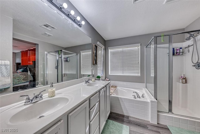 bathroom with hardwood / wood-style flooring, shower with separate bathtub, and a textured ceiling