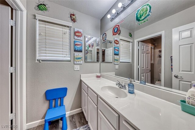 bathroom featuring toilet, vanity, a textured ceiling, and hardwood / wood-style flooring