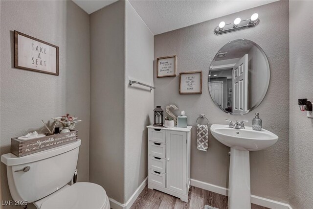 bathroom featuring toilet, wood-type flooring, a textured ceiling, and sink