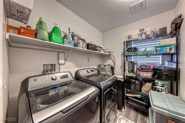 clothes washing area with a textured ceiling, light hardwood / wood-style flooring, and independent washer and dryer