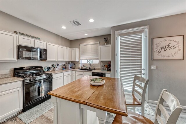 kitchen featuring light hardwood / wood-style flooring, white cabinets, black appliances, and sink