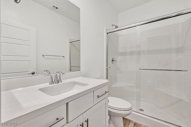 bathroom with toilet, a shower with shower door, wood-type flooring, and vanity