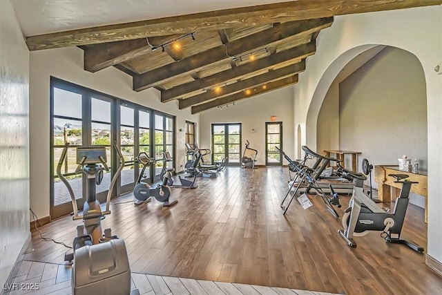 exercise room featuring a towering ceiling, rail lighting, and wood-type flooring