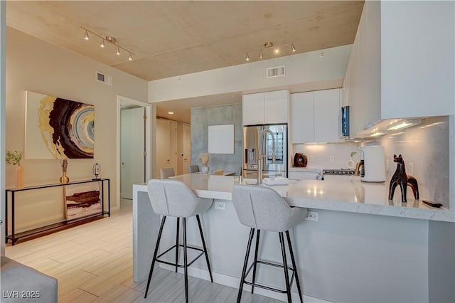 kitchen featuring a kitchen breakfast bar, kitchen peninsula, white cabinets, light hardwood / wood-style flooring, and sink