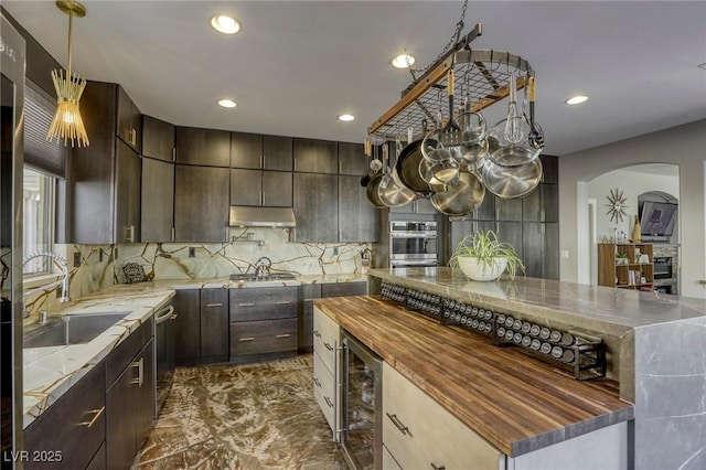 kitchen with sink, tasteful backsplash, dark brown cabinetry, wine cooler, and appliances with stainless steel finishes