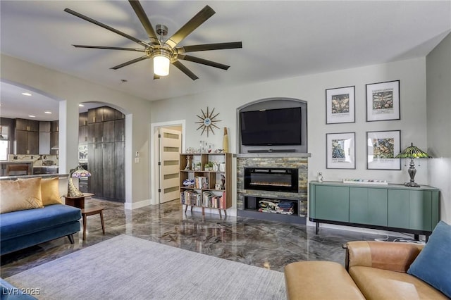 living room with ceiling fan and a stone fireplace