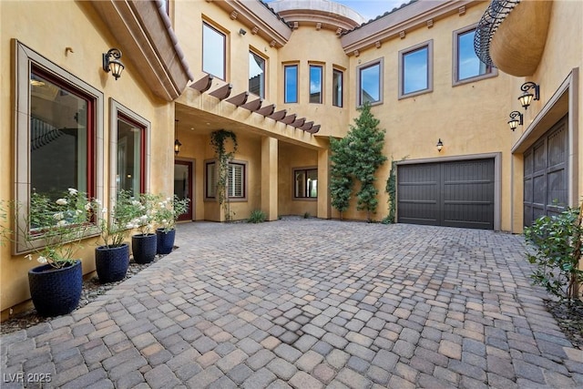 view of patio / terrace featuring a garage and decorative driveway