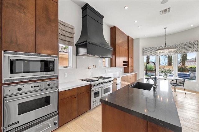 kitchen featuring custom exhaust hood, stainless steel appliances, visible vents, a healthy amount of sunlight, and a sink