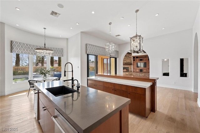 kitchen with a spacious island, a sink, brown cabinets, modern cabinets, and an inviting chandelier