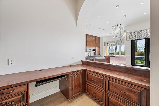 kitchen featuring light wood finished floors, wood counters, a sink, and recessed lighting