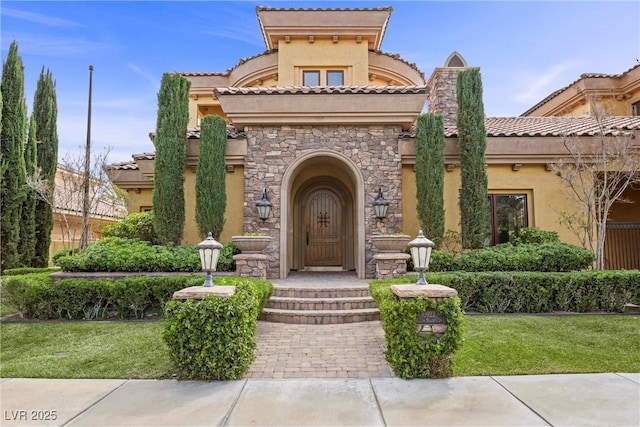 view of front facade featuring stone siding, a front yard, and stucco siding