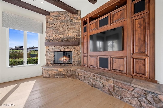 living room featuring beam ceiling, a fireplace, baseboards, and wood finished floors