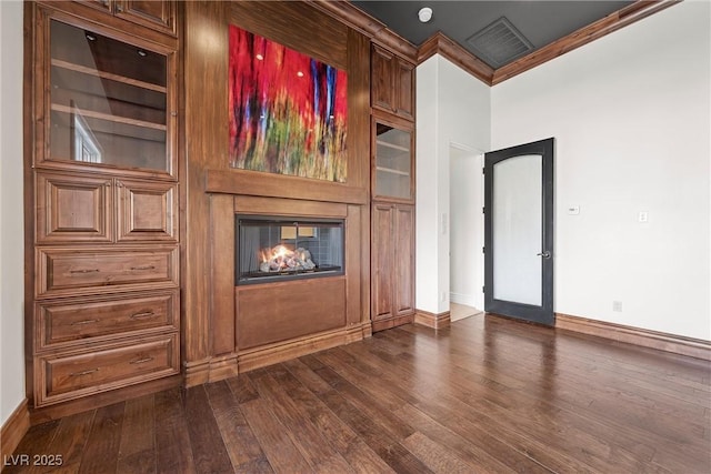 unfurnished living room featuring dark wood-style flooring, a multi sided fireplace, visible vents, baseboards, and crown molding