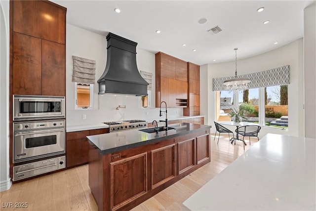 kitchen featuring a warming drawer, custom exhaust hood, visible vents, appliances with stainless steel finishes, and a sink