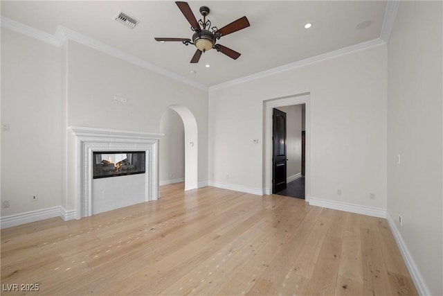 unfurnished living room with arched walkways, visible vents, crown molding, and light wood-style flooring