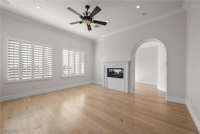 unfurnished living room with arched walkways, wood finished floors, visible vents, a multi sided fireplace, and ornamental molding