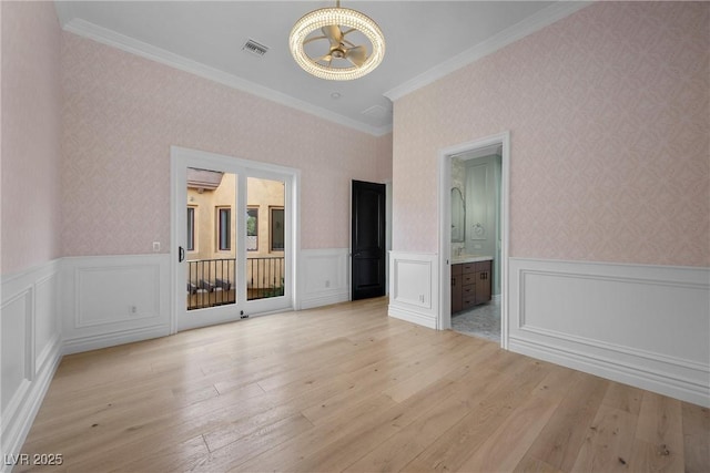 unfurnished bedroom with wallpapered walls, light wood-style flooring, visible vents, and wainscoting