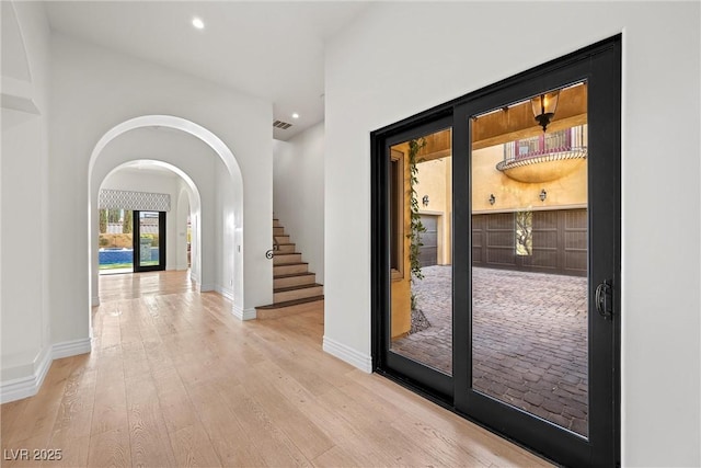 entryway with arched walkways, hardwood / wood-style flooring, recessed lighting, visible vents, and baseboards