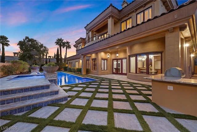 pool at dusk with a fenced in pool, french doors, a patio, and an outdoor kitchen