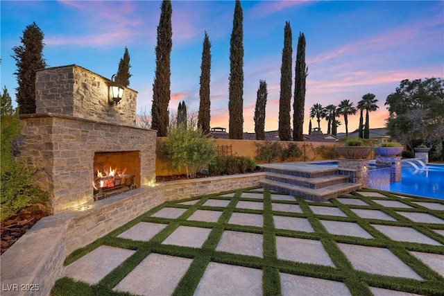 view of patio with an outdoor stone fireplace, a fenced backyard, and a fenced in pool