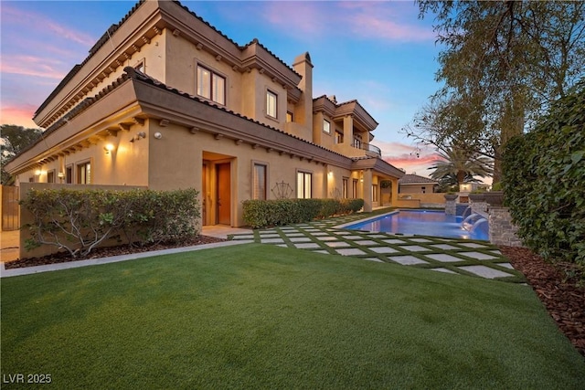 pool at dusk with a lawn, a patio area, and a fenced in pool