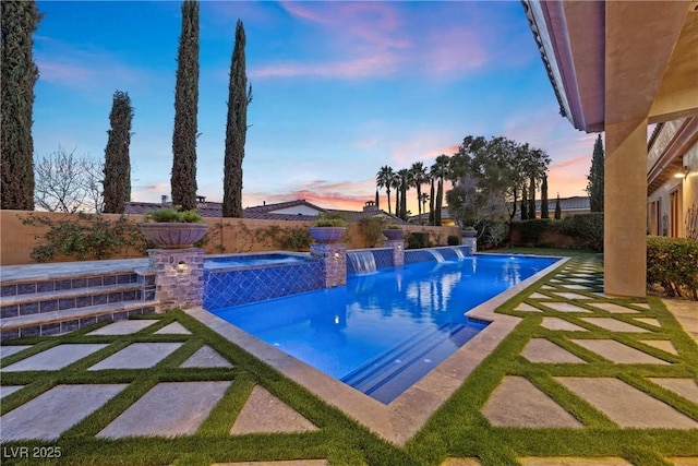 pool at dusk with a patio, a fenced backyard, and a pool with connected hot tub