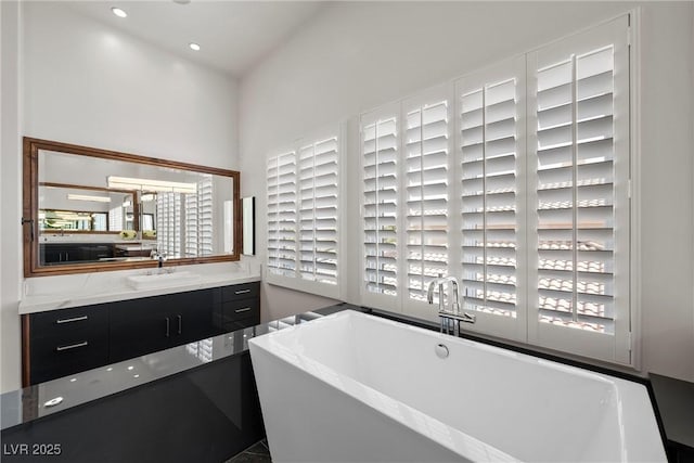 bathroom featuring a soaking tub, recessed lighting, and vanity