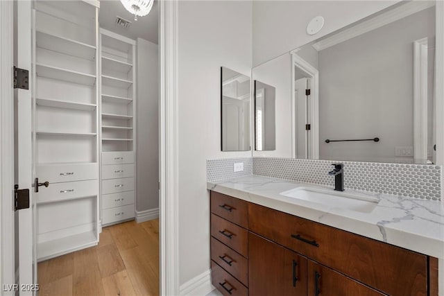 bathroom featuring visible vents, backsplash, wood finished floors, and vanity