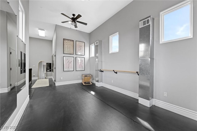 workout area with arched walkways, ceiling fan, and baseboards