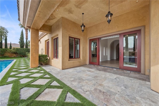 view of exterior entry featuring a patio, a fenced in pool, and stucco siding