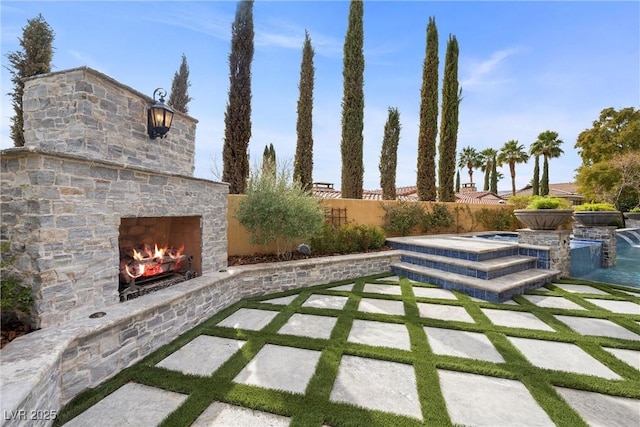 view of yard featuring a patio area, an outdoor stone fireplace, a fenced backyard, and an outdoor hot tub