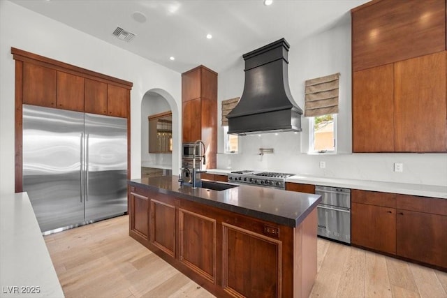 10923 Willow Heights Dr, Las Vegas, NV 89135 - kitchen featuring stainless steel built in refrigerator, custom exhaust hood, a sink, stove, and light wood-style floors