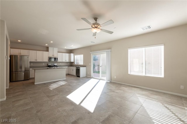 kitchen featuring stainless steel appliances, ceiling fan, a kitchen island, sink, and white cabinetry