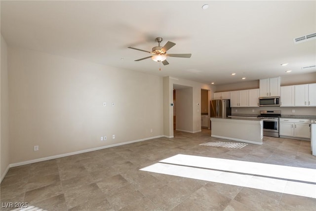 kitchen featuring a kitchen island, stainless steel appliances, ceiling fan, and white cabinetry