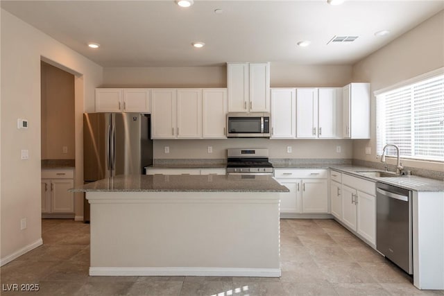 kitchen with sink, stainless steel appliances, white cabinetry, and a kitchen island