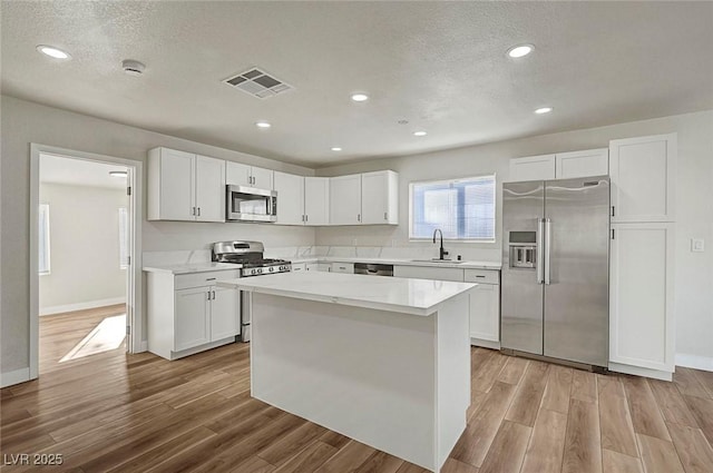 kitchen featuring stainless steel appliances, a center island, white cabinets, and sink