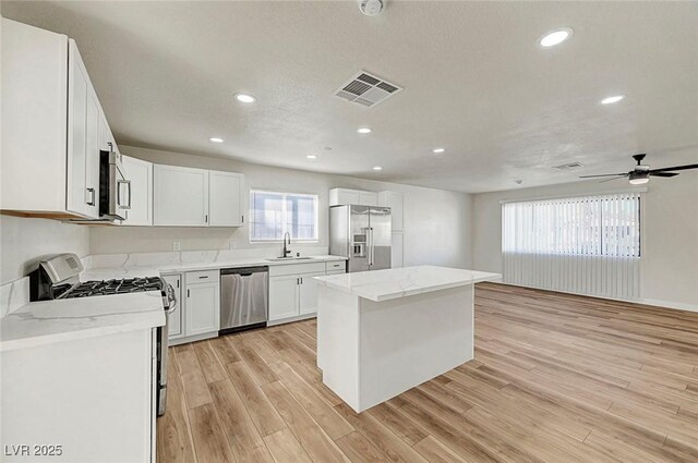 kitchen featuring sink, a center island, white cabinetry, light hardwood / wood-style floors, and appliances with stainless steel finishes