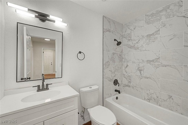 full bathroom featuring toilet, vanity, a textured ceiling, and tiled shower / bath combo