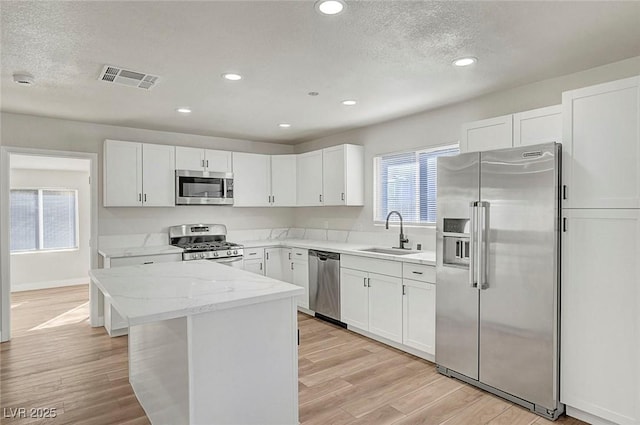 kitchen featuring stainless steel appliances, a kitchen island, white cabinetry, and sink