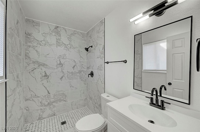 bathroom with tiled shower, vanity, and toilet