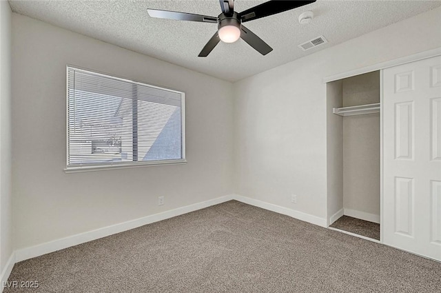 unfurnished bedroom with a textured ceiling, ceiling fan, a closet, and carpet