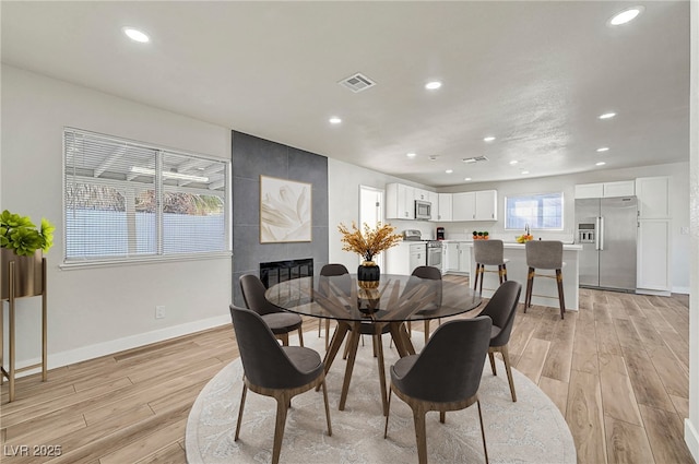 dining room with light hardwood / wood-style flooring and a fireplace